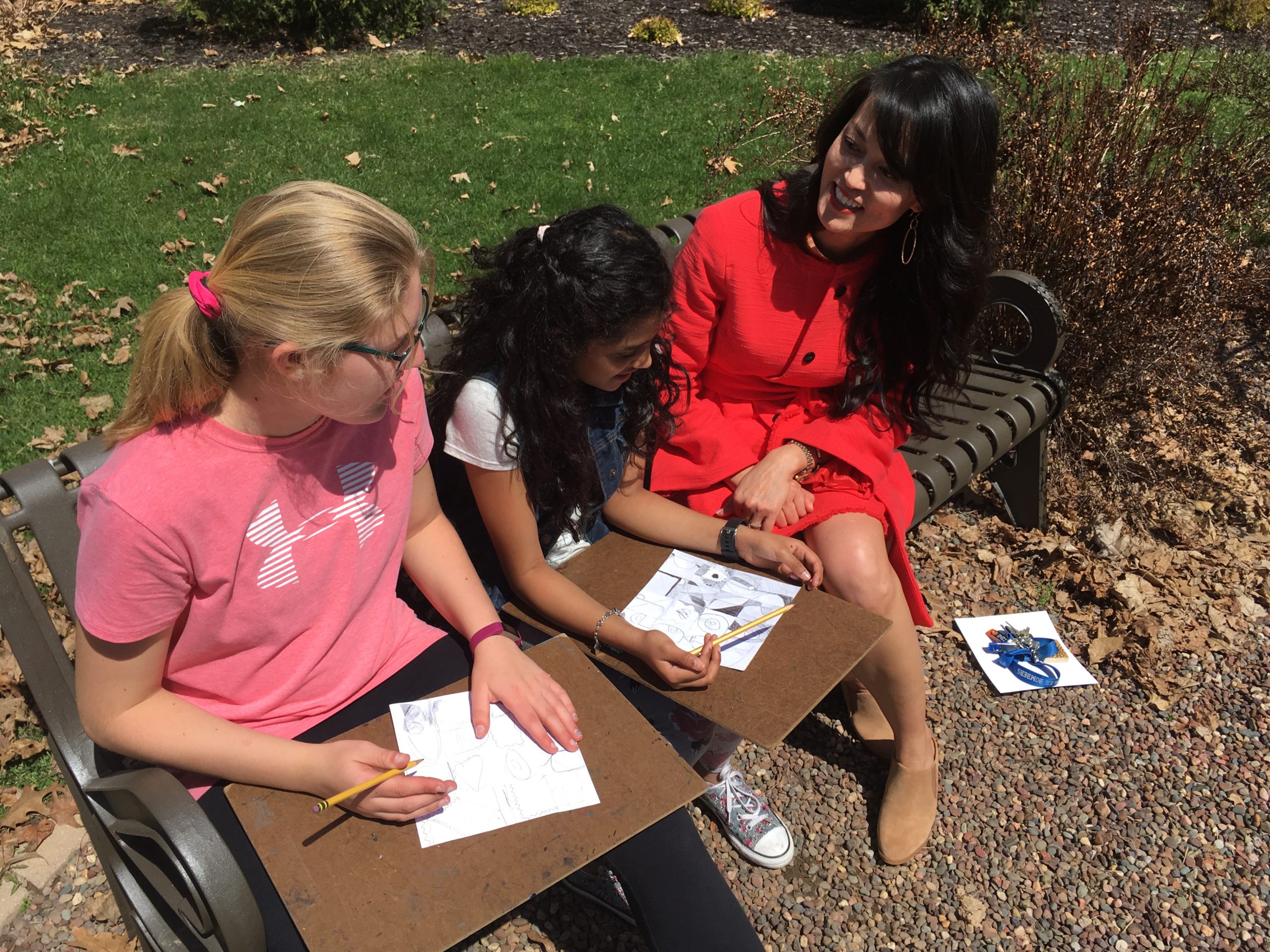 Students in an art class chat with the superintendent as they take advantage of a sunny spring day to sketch in the school's courtyard. 