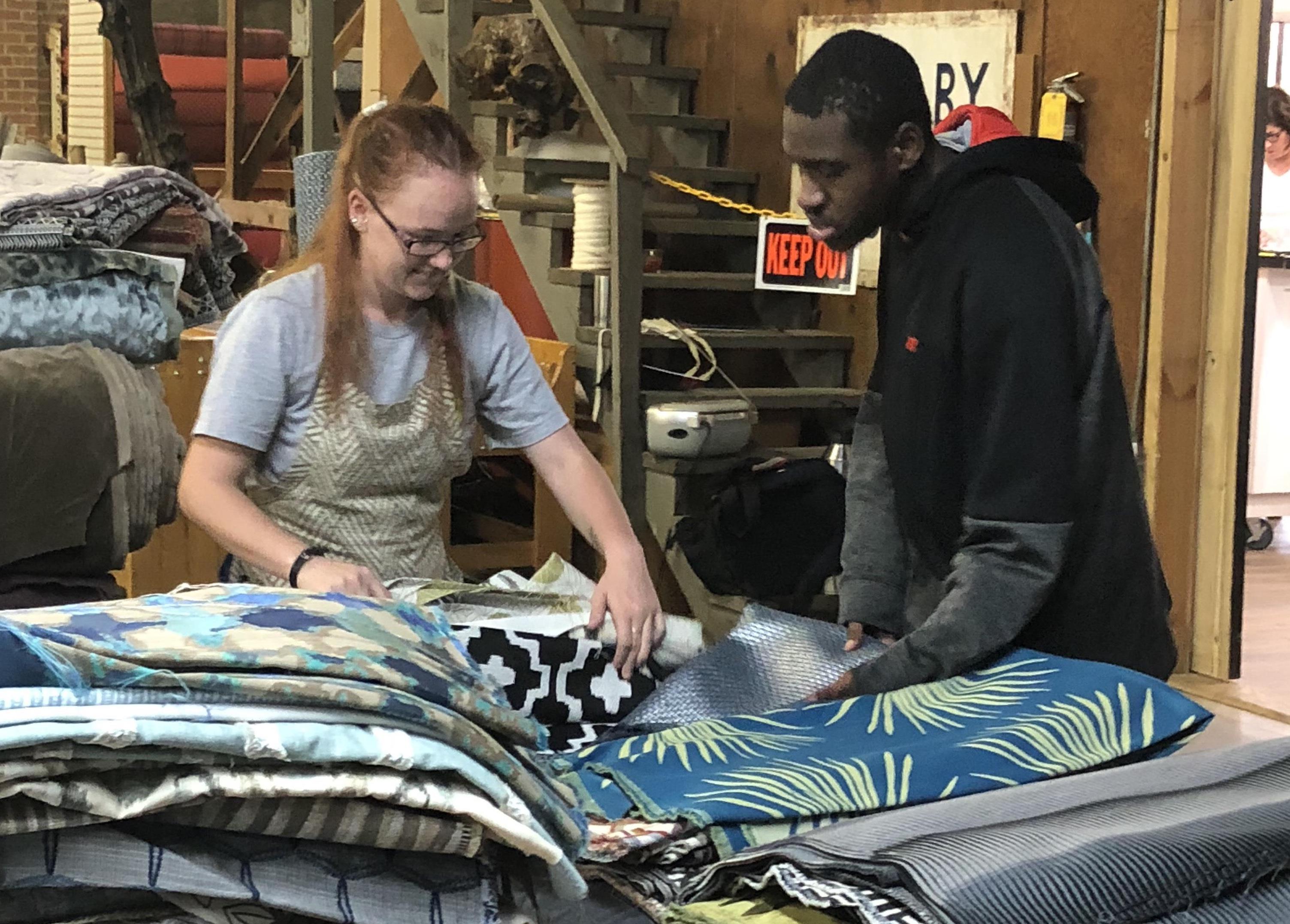 SPECIAL EDUCATION SUCCESS—A student (right) from Cleveland County Schools works with an employee at a fabric company. The North Carolina district’s Future Ready Occupational Course of Study program prepares special needs students for life after high school, with access to on-the-job experiences and related training in soft and hard skills.