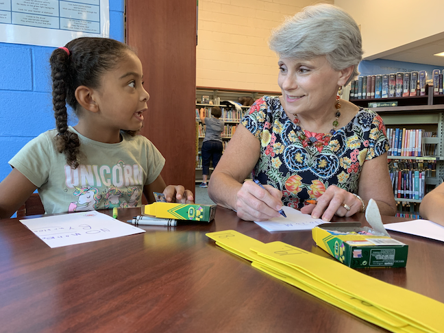 Hoover City Schools Superintendent Kathy Murphy and an elementary school student discuss their arts and crafts assignment in the library.