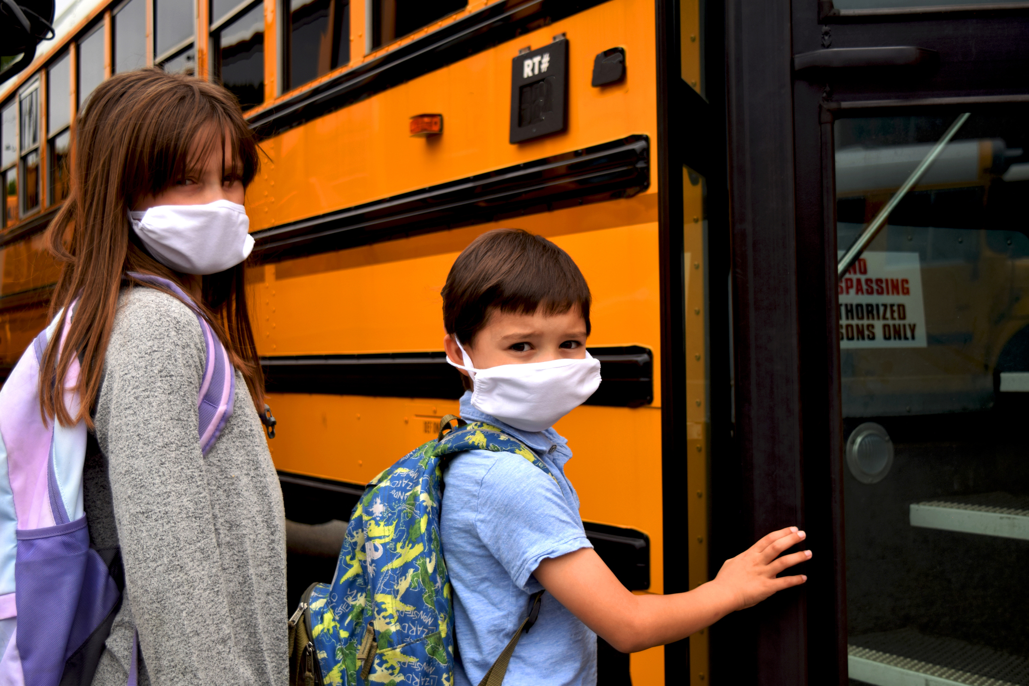 Two students wearing face masks board a school bus