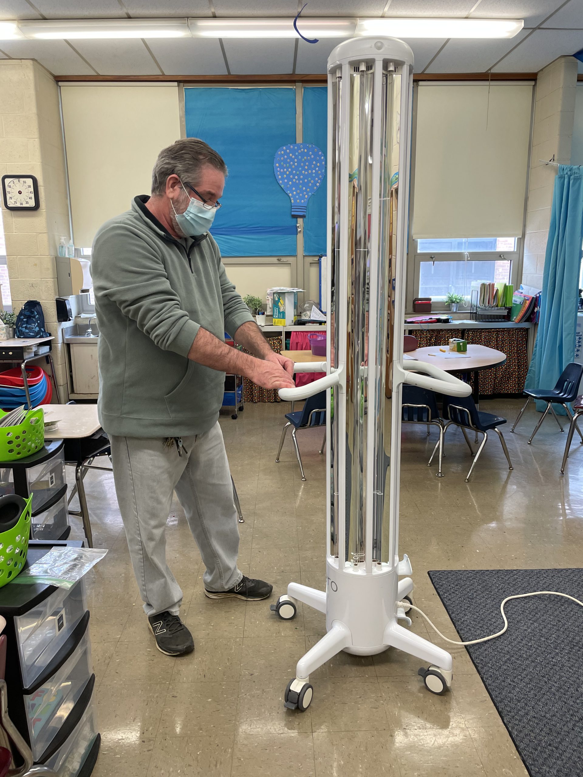 Joe Vecchio, the head custodian at Leedom Elementary, sets up an Arc UV-C unit in a classroom.